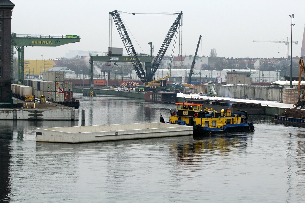 Blick in das Becken I des Berliner Westhafens am 18.01.2017. SB Birk-B (05801510) verholt eine  Beton-Wanne  in welche das Restaurantschiff Patio eingesetzt wird. Links zu sehen die auf Leichtern gestapelten Container.