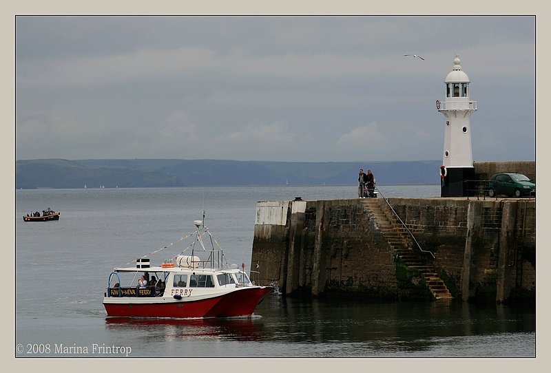 Mevagissey Cornwall UK - Hafeneinfahrt mit Leuchtturm. Mit dem kleinen Fhrschiff kann man zwischen Mevagissey und Fowley pendeln.