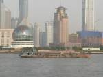 Einen interessanten Kontrast bildet dieses Transportschiff und im Hintergrund die moderne Huserkulisse von Shanghai. Fotografiert vom Bund aus, April 2006