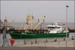 Fischereifahrzeuge Die HOO 70 ROYAL FRISK l�uft am 20.08.2008 in den Hafen von Hooksiel an der Jade ein. Am Horizont ist der hellblaue Rumpf eines gro�en Maersk-Containerschiffes zu sehen, das von Bremerhaven kommend in die Nordsee einl�uft. Dazwischen liegt das Wattgebiet 'Der Hohe Weg', nach dem auch ein Leuchtturm benannt ist.
