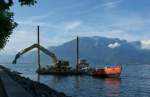 Der Kran auf dem Floss verteilt die Steine des Lastschiffes ...