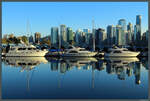 Mehrere Yachten spiegeln sich im Wasser des Coal Harbour vor der Kulisse der Downtown Vancouver.