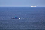 U-Boot vor Rgen mit erkennbarer Beflaggung und einer Fhre der UNITY LINE am Horizont.