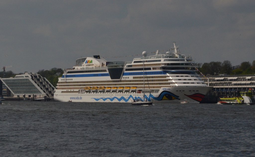 AIDAstella am Cruise-Terminal in Hamburg-Altona. Am Heck sieht man das schrge  Docklandhaus und  am Bug ein Fhrschiff. Am   05.05.2013 beobachtet.