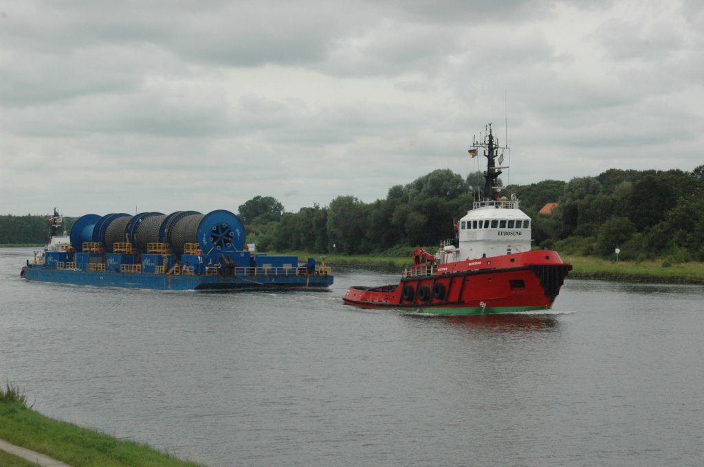 Am 27.07.2011 auf dem NOK kommen lange Seekabel fr die Anbindung der Offshore-Windparks, von nkt. Der deutsche Windpark Baltic 2 (ehemals Kriegers Flak) wird in der Ostsee ca. 32 km nrdlich der Insel Rgen gelegen sein. 80 Windmhlen werden eine Flche von 27 Quadratkilometern bedecken mit einer Kapazitt von 288 MW. Rund 340.000 Haushalte knnen damit versorgt werden. Der Schlepper Storesund hinten hat sich versteckt und der Schlepper Eurosund vorn zieht den antriebslosen Kahn. 