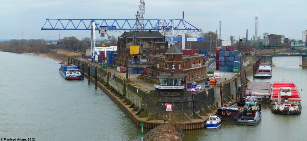 Der Hafenkopf des Krefelder Rheinhafen von der Uerdinger Rheinbrcke aus gesehen, 11.03.2012. Rechts die Einfahrt zum Rheinhafen, links der Rhein stromaufwrts. Containerschiff Paradox wird gerade beladen.