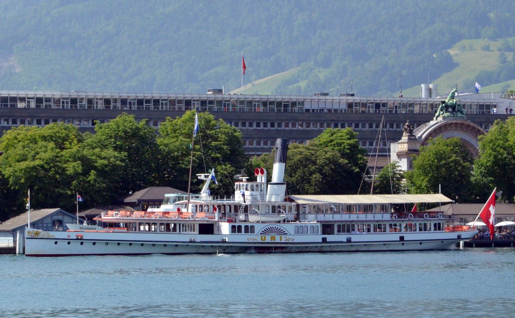 Der Schaufelraddampfer ,,URI´´ auf dem Vierwaldstätter See in Luzern, im Hintergrund erinnert die historische Eingangspforte auf dem Bahnhofplatz vom  alten,1896 eröffneten Bahnhof. Abgelichtet am 18.06.2013.