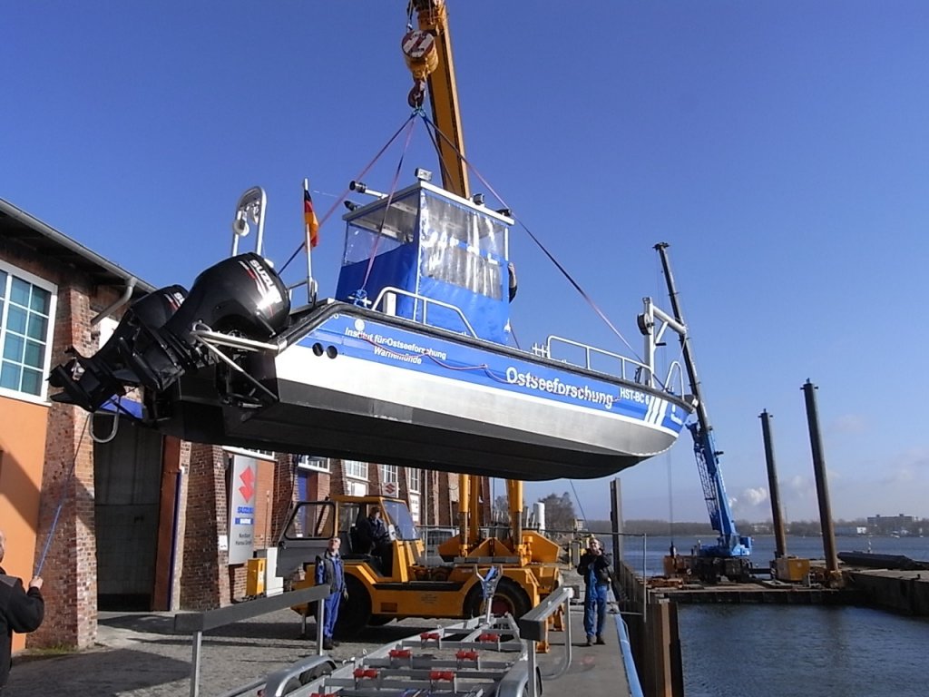 Ein Motorboot wird hier mit einem Autodrehkran ins Wasser gehoben. Das Boot ist ein Doppelrumpfboot aus Alu, unterwegs mit 2x70 PS Suzuki Auenbordmotoren. Das Fahrzeug ist ein Einsatzmittel fr das Institut fr Ostseeforschung Warnemnde.