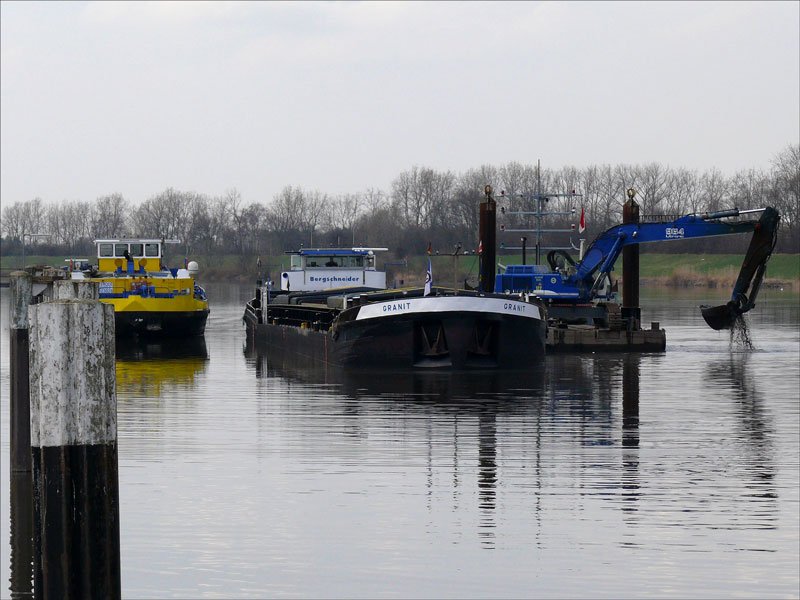 Mit einem LIEBHERR-Bagger wird von einem Ponton aus die Elbe ausgebaggert und das Gut auf die GRANIT der Fa. Bergschneider gebracht, links daneben liegt die ASTERODE; Geesthacht, Unterer Schleusenkanal, 26.03.2010
