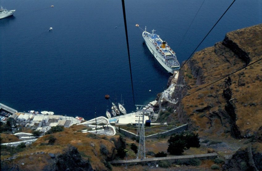 Nach dem ankern an der Kykladeninsel Santorin geht es mit einer Kabinenbahn hinauf zum Ort Santorin. Aus der Kabine der Bahn geht der Blick zurck hinunter an die Anlegestelle, wo einige Segelboote und ein Kreuzfahrschiff liegen. (Mai 1996)
