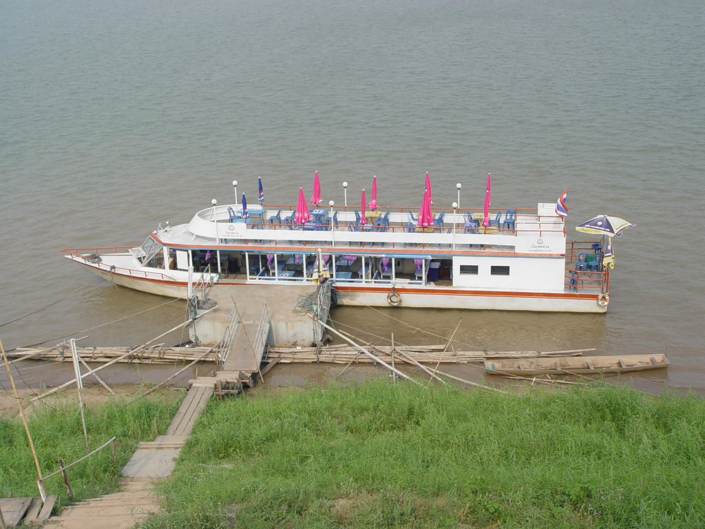 Niedrigwasser auf dem Mekong. In der Flumitte bei Nong Khai / Thailand ragt die Spitze eines Tempelchedi aus dem Wasser, zu dem viele glubige Thais mit diesem Motorboot bersetzen. 