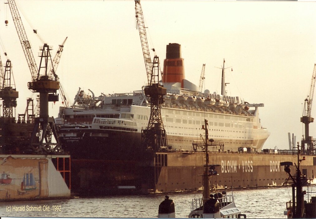 QUEEN ELIZABETH 2  IMO 6725418 im Oktober 1992 in Dock 11 von Blohm&Voss, Hamburg / 
Cunard Line / bei John Brown& Co, Clydebank, Nr. 736 / 18.4.1969 Ablieferung / BRT 65863 / Lüa. 293,53, B 32,01, Tg. 9,87m, / 2 Satz Getriebeturbinen, 110.000 PS, 2 Prop. 28,5 kn / 1986/87 bei Lloyd Werft, Bremerhaven auf dieselelektrischen Betrieb umgebaut, neun 9-Zyl. MAN/B&W, 95.650 kw, 2 E-Motore, 86770 kW, 28,5 kn / BRT 66.450 / 2.10.1992 nach Reparatur bei Blohm&Voss, Hamburg, BRZ 69.053  / 12.1994 BRZ 70.327 / 27.11.2008 Außerdienststellung / Umbau zum Hotel-Schiff /
 (Scan vom Foto)