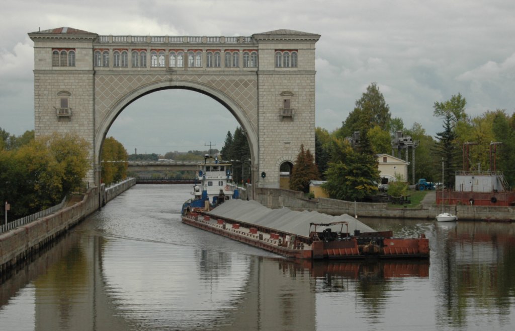 Vor Uglitsch passieren wir mit unserer MS Scholochow die Uglitscher Einkammerschleuse, wo die Schiffe um 11 m gesenkt werden. Bei der Einfahrt in die Schleuse sieht man einen Triumphbogen, der an den Sieg ber Deutschland im II. Weltkrieg erinnern soll. ber die Trme des unteren Schleusentores fhrt eine Autostrasse. Diese Schleuse ist 290 m lang, 30 m breit und 5,5 m hoch. Die 1940 fertig gestellte Anlage wird jetzt von nur 2 Personen gesteuert und berwacht.
Hier das Auslaufen eines Schubverbandes aus der Schleusenkammer. Aufgenommen am 13.09.2010.