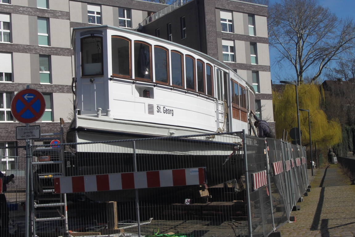 „Alsterdampfer“ ST.GEORG; Eigner/Betreiber: Verein Alsterdampfschiffahrt e.V.; Datum: 20.03.2026; Aufnahmeort: Osterbekkanal/Hamburg, Deutschland.
Am ältesten noch fahrtüchtigen Dampfschiff Deutschlands wurde kurz vor Saisonbeginn eine Leckage festgestellt. In Ermangelung eines schnell verfügbaren Werftplatzes wurde das Schmuckstück kurzerhand per Kranwagen aus dem Osterbek-Kanal im Stadtteil Barmbek gehievt und in einer Wohnstraße direkt am Kanal ein provisorisches Dock eingerichtet.
