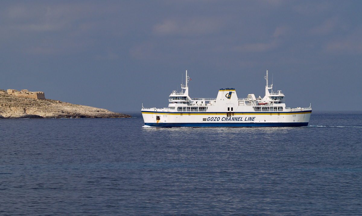 Am 02.10.2007 kommt die Ta’Pinu (IMO 9176307), Namensgeber der gleichnamigen Schiffsklasse aus 3 Fährschiffen, auf ihrer Fahrt von Sa Maison auf der Hauptinsel nach Mġarr an der Südwestspitze von Gozo vorbei, links ist noch die St. Anthony Battery zu sehen. Die Strecke zwischen Mġarr und Sa Maison in der Nähe der Hauptstadt Valetta ist erheblich länger als die kurze Fahrt über den Gozokanal und wurden vor allem für den Schwerverkehr durchgeführt, der den Weg über die engen und steilen Straßen nach Ċirkewwa einsparen konnte. Das Foto ist von der kleinen Insel Comino entstanden, man hat von dort einen idealen Blick in Richtung Gozo.