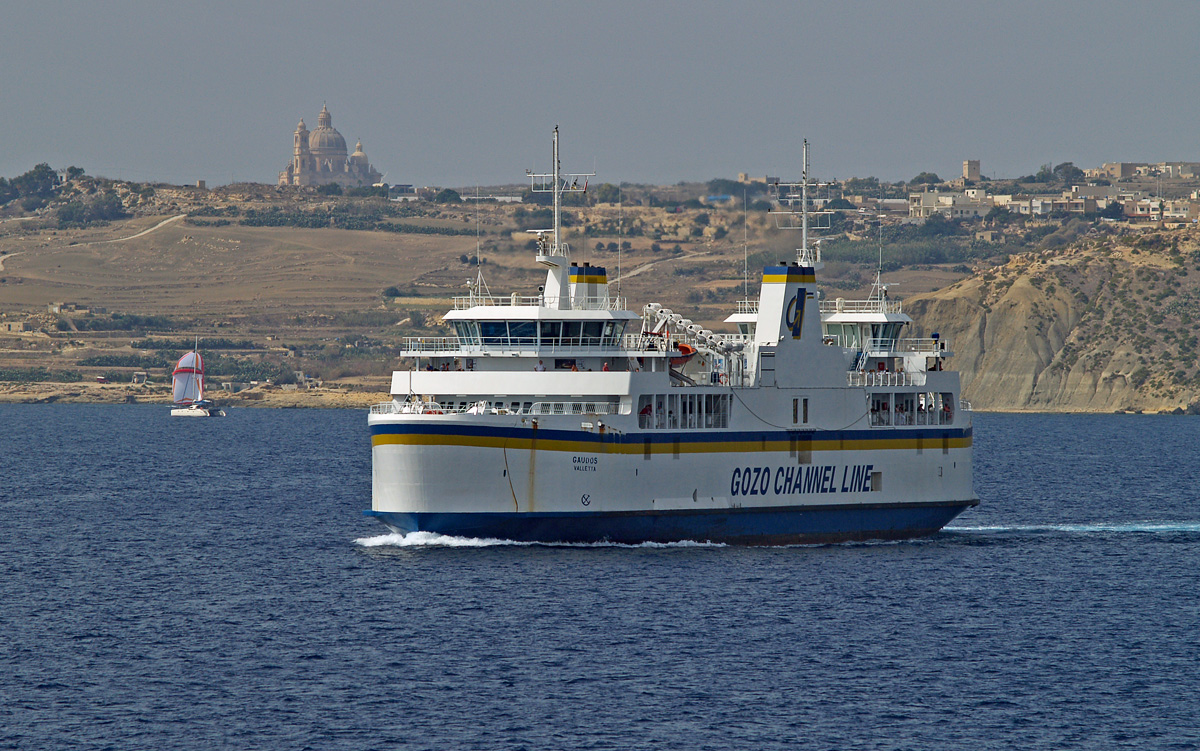 Am 29.09.2007 ist die Doppelendfähre GAUDOS (IMO 9176319) auf dem Weg von Mġarr nach Ċirkewwa durch den Gozo-Kanal, im Hintergrund gibt Gozo mit der prächtigen Kirche von Xewkija, die Johannes dem Täufer geweiht ist, ein passables Panorama. 