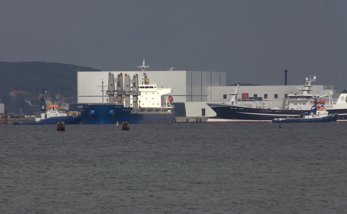 Blick auf den Hafen Sassnitz/Mukran. Lowaland Scheldt wird gerade aus dem Hafen geschleppt,  Schlepper Argus und Heros sind im Einsatz, am Kai liegt HG 268 Ruth, ein dänisches Fischereifahrzeug, für einen  Nichtschiffskenner  schwer ersichtlich. 12.08.2016 15:38 Uhr  Teleaufnahme vom Badestrand Neu Mukrahn. 