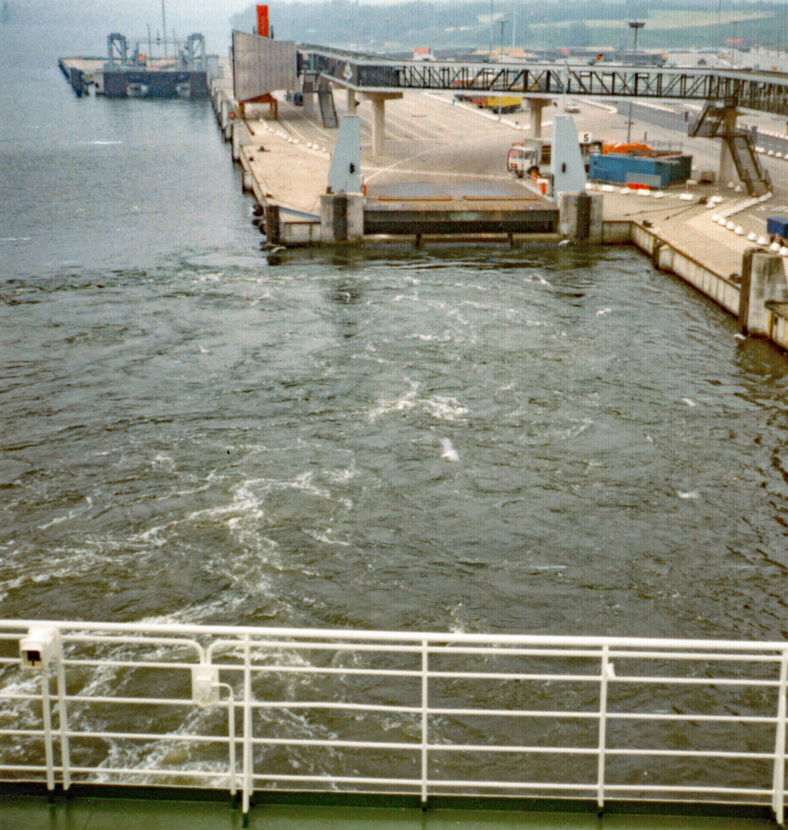 Blick von MS Peter Pan auf einen Teil des Lübecker Skandinavienkais in Travemünde. Das zur TT-Line gehörende Fährschiff hat gerade abgelegt. Aufnahme aus dem Jahr 1979. Die eingeschränkte Bildqualität ist meiner einfachen Kamera geschuldet. Etwas  Besseres  konnte ich mir damals als Schüler nicht leisten.