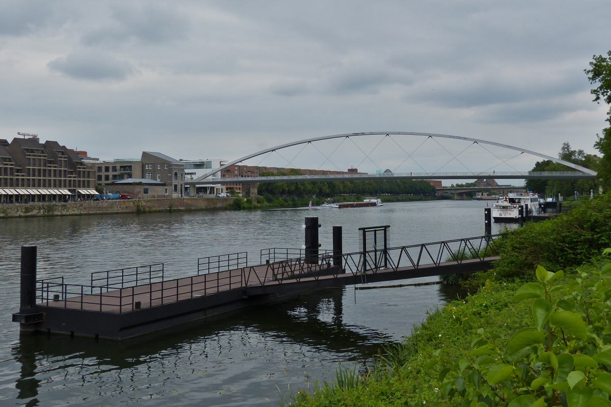 Blick ber die Maas in Maastricht mit im Vordergrund einen Bootsanleger fr Boote zu Fluss Rundfahrten, im Hintergrund die Fahrrad und Fugngerbrcke zum berqueren des Flusses. 17.07.2020