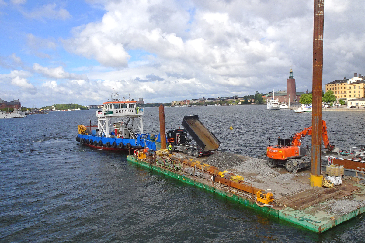 Das Arbeitsboot  Dunder  der Firma Züblin half 2021 bei den Bauarbeiten rund um die Södra Järnvägsbron, welche Stockholm C mit dem Süden Schwedens verbindet. Der Blick geht auf den Mälarsee, rechts im Hintergrund das Rathaus von Stockholm.
Stockholm, Schweden, 25. August 2021