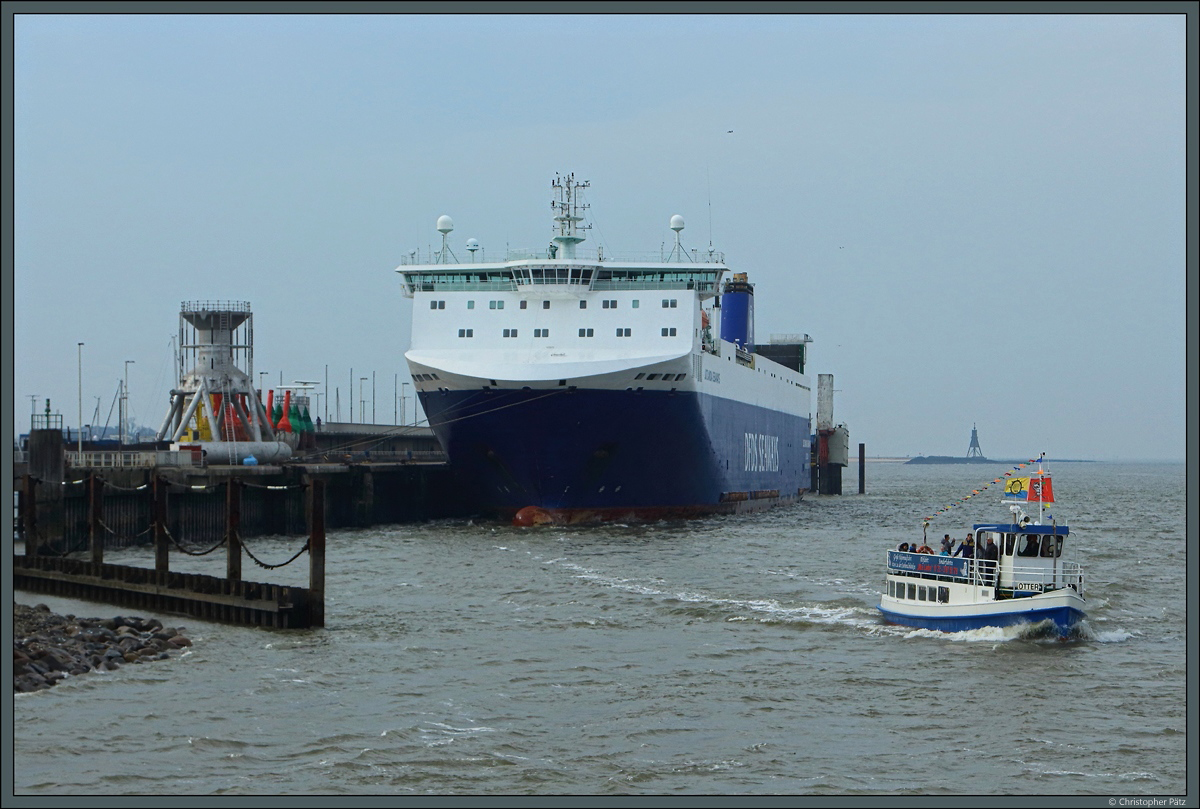 Das kleine Ausflugsschiff  Otter  passiert das RoRo-Schiff  Jutlandia Seaways  der Reederei DFDS Seaways. Im Hintergrund ist die Kugelbake als eines der Wahrzeichen Cuxhavens zu sehen. (12.04.2018)