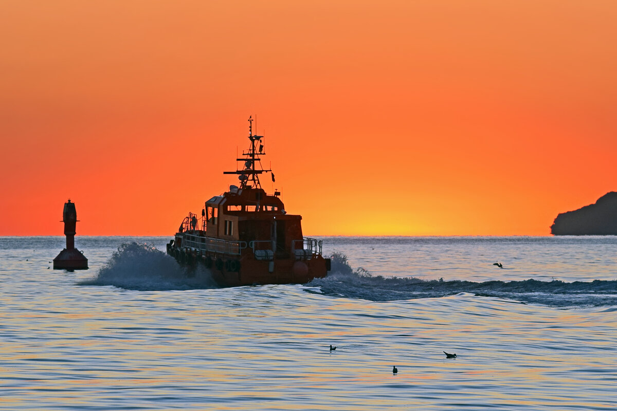 Das Lotsenversetzboot BÜLK fährt im Licht der aufgehenden Sonne auf die Ostsee hinaus. August 2022