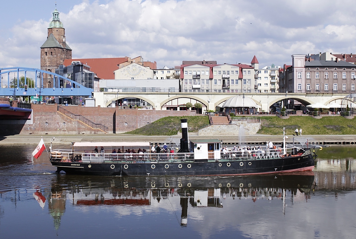 Das polnische Museums- und Ausbildungsschiff KUNA am 03.05.2016 auf der Warthe in Gorzow Wielkopolski/Landsberg an der Warthe. Das Schiff hat eine abwechslungsreiche Geschichte: Gebaut wurde es 1884 von der Danziger Schiffswerft & Kesselschmiede Feliks Devrient & Co. als Dampfeisbrecher für die Königlich Preußische Weichsel-Strombauverwaltung. Es erhielt den Namen  FERSE  nach einem Weichselzufluß. 1920 wurde es an den Hafenrat und die Wasserstraßen der Freien Stadt Danzig übergeben. Von 1939 bis 1945 gehörte das Schiff zur Hauptwasserstraßenbehörde des Deutschen Reiches und erhielt den Namen  MARDER . Im März 1945 war es an der Evakuierung der Danziger Bevölkerung beteiligt und kam so nach Kiel bzw. Hamburg. Es folgte ein Einsatz als Hafenschlepper und Eisbrecher in Hamburg. 1947 kehrte das Schiff auf dem Seeweg nach Danzig zurück und wurde von der Verwaltung der Binnenwasserstraßen auf der unteren Weichsel unter dem Namen KUNA (das polnische Wort für  Marder ) bis zur Abstellung 1965 eingesetzt. Ohne Ausrüstung und Aufbauten wurde der frühere Eisbrecher in den siebziger Jahren in Gorzów Wielkopolski als Festmacherponton verwendet. Dieser sank 1981, 2000 wurden die Reste gehoben und äußerlich in der Ursprungsform wieder aufgebaut, als Antrieb dient heute allerdings ein 165 PS-Dieselmotor.
