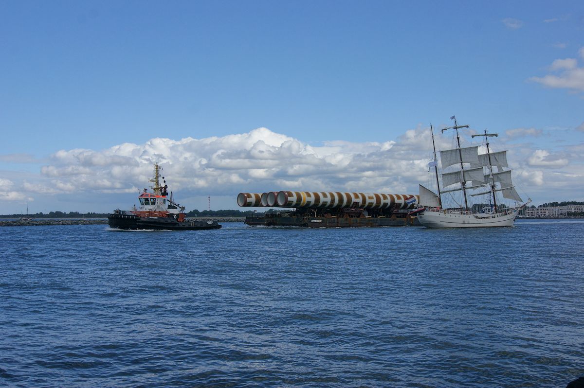 Der Schlepper Bugsier 10 zieht ein Ponton mit Masten für Hochseewindparks durch den Seekanal Warnemünde und begegnet dabei der 3-Mast Bark Artemis. (14.08.2016)