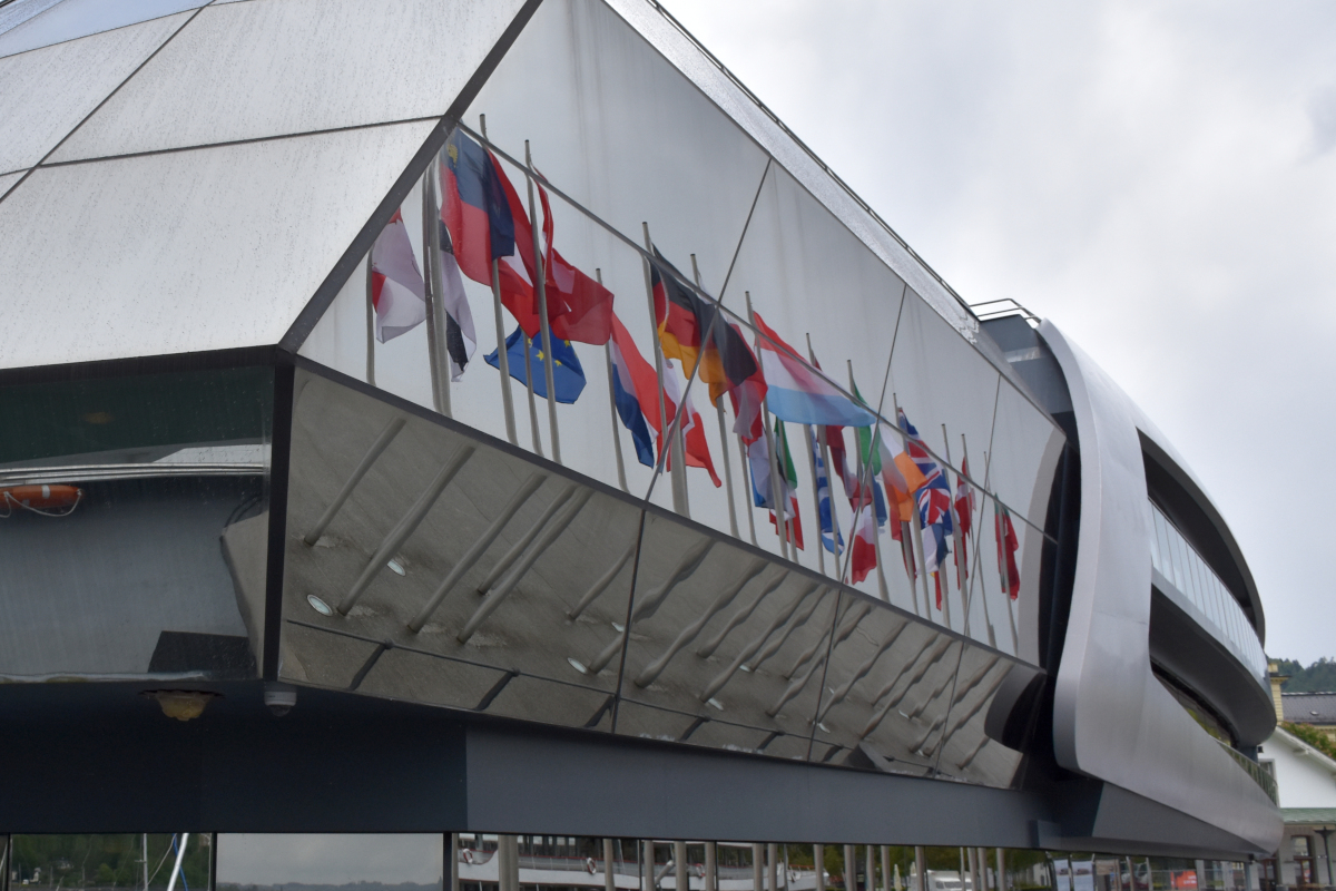 Die Flaggen im Hafen von Bregenz spiegeln sich auf der Außenhaut der MS SONNENKÖNIGIN. 2019-05-05