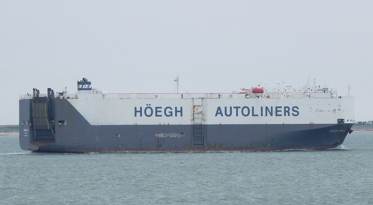 Die  HÖEGH OSLO , IMO 9382396, am 22.07.22 vor der holländischen Küste bei Cadzand Bad. Das Schiff ist ein Autotransporter mit einer Kapazität von 5400 ceu. Das steht für Car Equivalent Unit (engl., Abkürzung CEU, deutsch etwa Standard-PKW-Einheit) und zeigt an, wie viele Fahrzeuge transportiert werden können. Das Schiff fährt unter der Flagge von Norwegen und wurde im Jahr 2008 von  TSUNEISHI HEAVY INDUSTRIES  in BALAMBAN auf den Philippinen gebaut.
