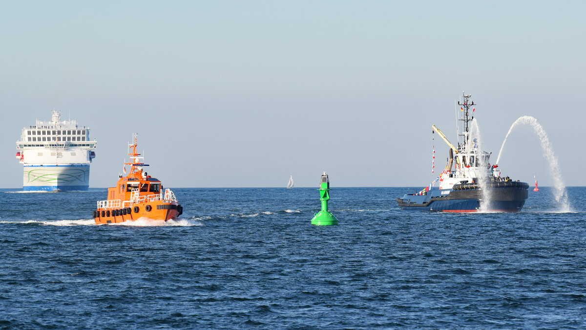 Die neue NILS HOLGERSSON (IMO 9865685) läuft am 20.04.2022 erstmals Lübeck-Travemünde an. Vor dem TT-Line-Fährschiff ist das Lotsenversetzboot BÜLK zu sehen. Rechts im Bild begrüßt der Schlepper VB ARGUS das  Green Ship  