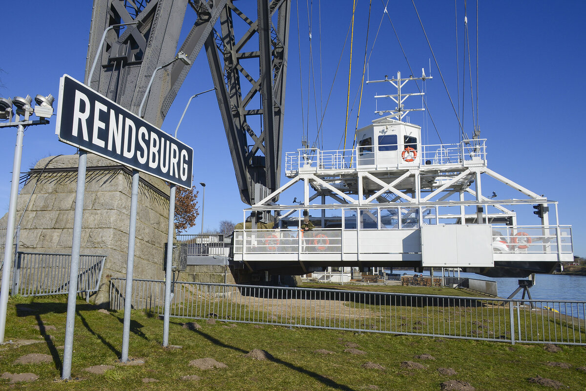 Die neue Schwebefähre unter der der Rendsburger Hochbrücke. Mehr als sechs Jahre lang gab es keine direkte Verbindung zwischen Osterrönfeld und Rendsburg. Die Rendsburger Schwebefähre war im Januar 2016 mit einem Frachtschiff kollidiert. Dadurch war sie so schwer beschädigt, dass die Fähre nicht mehr fahren konnte und eine neue gebaut werden musste. Rund 13 Millionen Euro kostet die neue Schwebefähre. Aufnahme: 7. März 2022.