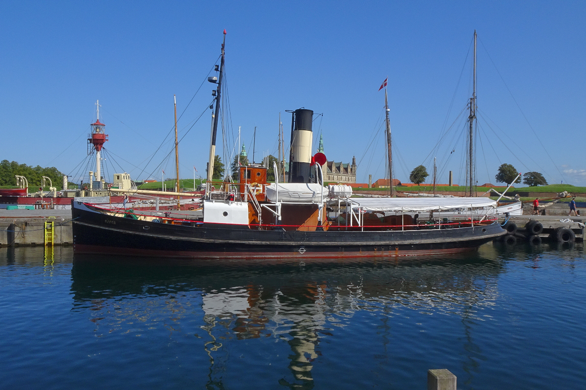 Ein wahres Kleinod ist der Dampfeisbrecher und Schlepper  Björn  aus dem Jahr 1908 im Museumshafen des dänischen Helsingör. Er ist fahrfähig und kam erst wenige Tage zuvor von einer Seereise nach Jütland zurück. Der Kessel war noch warm. Angetrieben wird das Schiff von einer stehenden Dreifach-Expansions-Dampfmaschine, also einer Dampfmaschine mit Hochdruck- Mitteldruck- und Niederdruckzylinder. Der Kessel versorgt die Maschine mit Sattdampf von 13 kg/cm² Überdruck, was einer Temperatur von etwa 190 Grad Celsius entspricht. Auch sämtliche Hilfsmaschinen, Speisepumpe, Generator, Capstan... werden mit Dampf betrieben.
Die freundlichen Betreiber des Schiffes erklärten mir, daß die Björn jeden ersten Sonntag im Monaten mit Passagieren für etwa drei Stunden in See sticht.
Dampfschiff Björn, Helsingör, DK, 2. September 2023