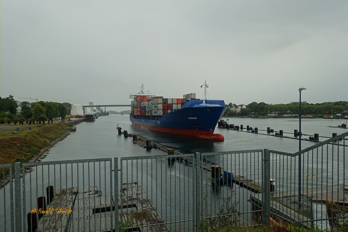 ELBWATER  (IMO 9504073) bei strömendem Regen am 8.9.2022, Schleuse Kiel-Holtenau, die Schleusenkammer ansteuernd /

ex-Namen: WES JANINE (2021), WES J (2019), WES JANINE (2016) /

Containerschiff/Feeder / BRZ 10.585 / Lüa 151,72 m, B23,4 m , Tg 8 m / 1 Diesel MAN-B&W 8L48/60B, 9.000kW (12.236 PS), 18,5 kn / 1.036 TEU, davon 250 Kühlcontainer / gebaut 2012 bei Jiangdong-Werft Wuhe, China / Eigner + Manager: Wessels Reederei - Haren Ems, D. /  Flagge: Zypern, Heimathafen: Limassol  / 
