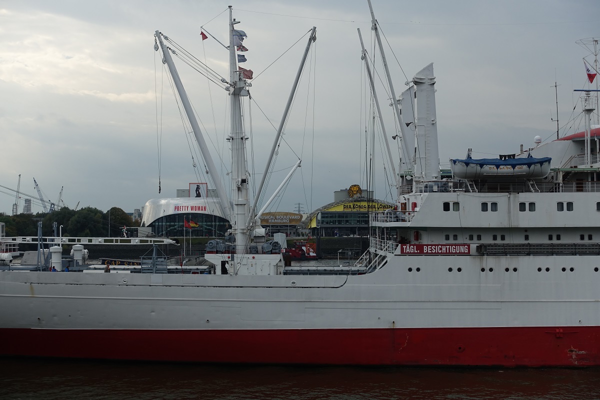 Hamburger Elb-Impression: Blick von der Hochwasserschutzpromenade Niederhafen durch das Ladegeschirr der CAP SAN DIEGO an der Überseebrücke liegend zu den Hafentheatern auf der anderen Seite der Elbe im Stadtteil  Steinwerder /