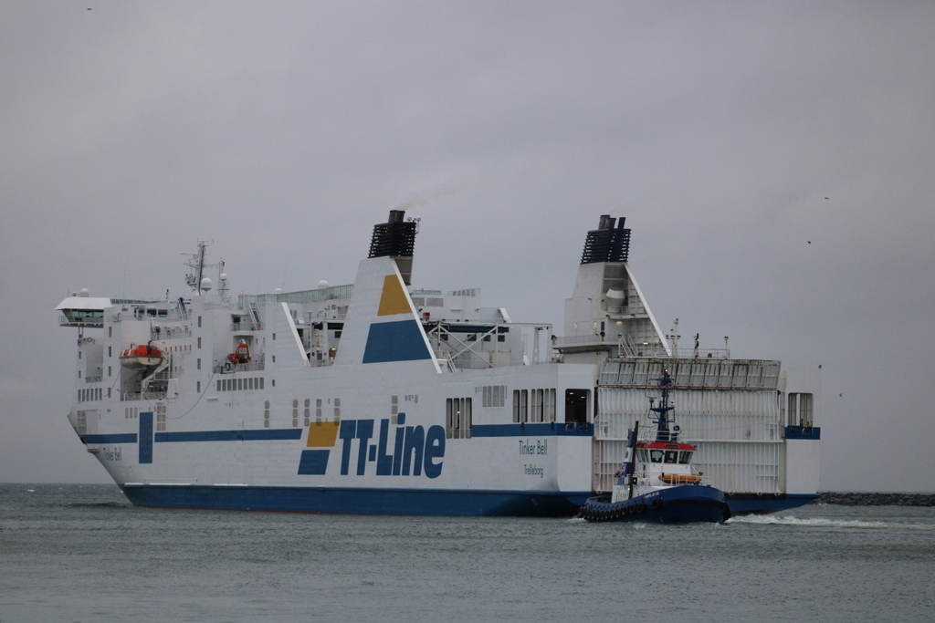 Heckansicht der TT-Line Fähre Tinker Bell(Heimathafen Trelleborg)am 17.02.2023 in Warnemünde mit dem Schlepper Fairplay 56