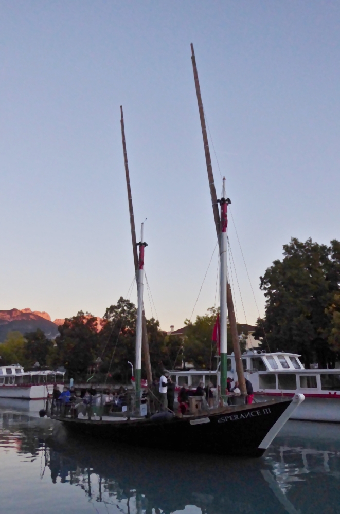 Im letzten Abendlicht kehrt der 2 Mastsegler Espérance lll, an die Anlegestelle nahe Annecy zurück. 19.09.2022 
Das Schiff ist ein Nachbau der Espérance II welches von 1910 bis 1930 auf dem See verkehrte. Das Boot wird ausser den Lateinersegeln von einem Elektromotor angetrieben. (Quelle Wikipedia) 