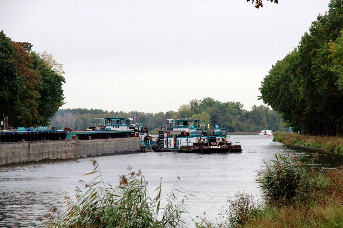 Paket-Übergabe der nicht alltäglichen Art im Sacrow-Paretzer-Kanal  /  UNTERE HAVEL-WASSERSTRASSE  am 04.10.2021 Höhe Schlänitzsee. Der zu Berg fahrende Schubverband mit dem Schubboot  EDO  (05608640) und das Schubboot  EDWALD  stoppten , es wurde ein kurzes Schwätzchen gehalten und die Ware wechselte das Schubboot.