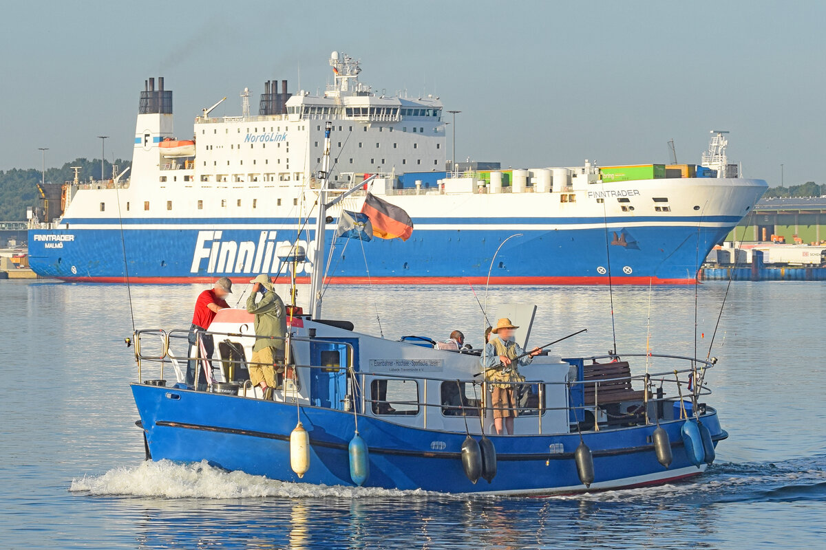 PROF. OEFTERING fährt mit Angelgästen am 4.8.2022 von Travemünde auf die Ostsee hinaus. Im Hintergrund ist die Finnlines-Fähre FINNTRADER zu sehen