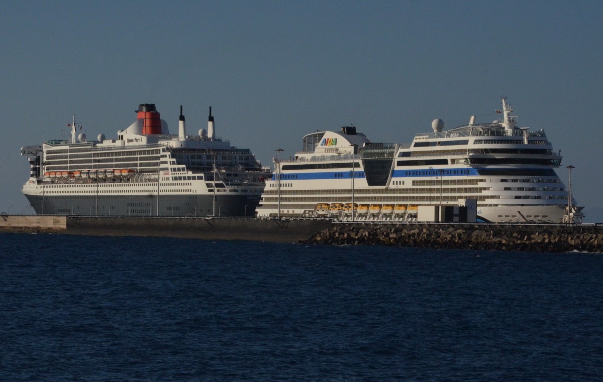 Queen Mary 2 in Arrecife / Lanzarote am 10.12.15. IMO: 9241061, Länge 345,03 m,  Breite  41,15 m, Tiefgang max. 9,75 m, mit Heck an Heck von AIDA Sol
IMO: 9490040, Länge 253,33 m, Breite 32,20 m, Tiefgang max. 7,3 m.
