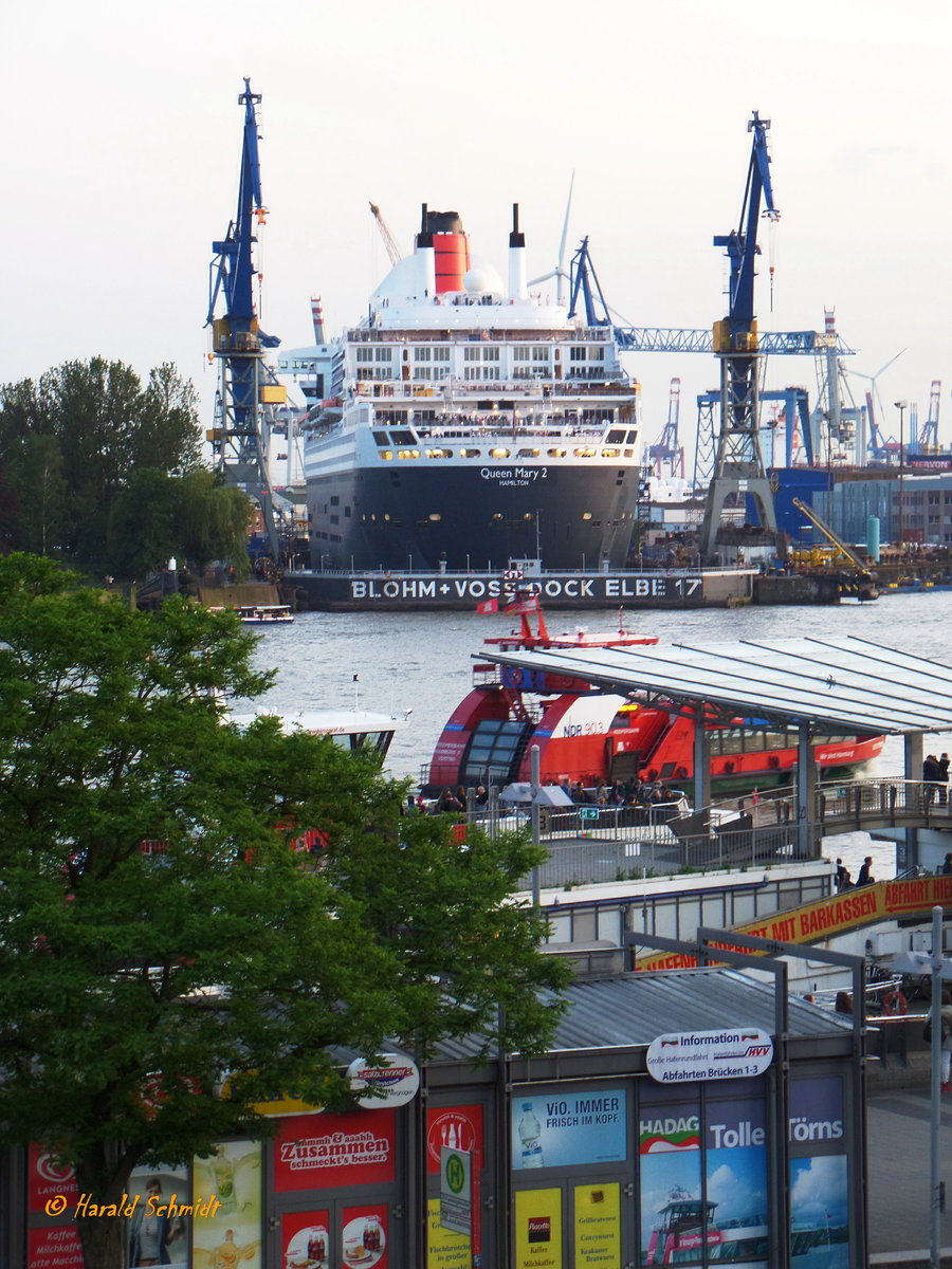 QUEEN MARY 2 (IMO 9241061) am 27.5.2016, Hamburg, Elbe / Eindocken in das  Trockendock Blohm+Voss  Elbe 17 / eindockung abgeschlossen, Blick von den St. Pauli Landungsbrücken nach Steinwerder /

Passagierschiff / Cunard Line / 148.528 BRZ / Lüa 345,03 m, B 41 m, Tg  m / 4 Diesel, Wärtsilä 16V46C, ges. 67.200 kW (91.392 PS), 2 Gasturbinen, GE Marine, LD 2500 T ges. 59.660 Kw (81.115 PS), ges. 126.870 kW (172.495 PS), 4 E-Fahrmotore 86.000 Kw (116.927 PS), 4 Pods, 26,5 (30) kn /  2705 Pass. / gebaut 2003 bei Chantiers de l ´Atlantique, St. Nazaire / Heimathafen: Southampton  bis 2011, Hamilton, seit 2011 / 
2016 Umbau + Generalüberholung für ca. 100 Mill. Euro bei Blohm + Voss, Hamburg, Master Refit mit u.a. 50 neue Kabinen, 4 neue Abgaswaschanlagen (Scubber) + Abgasfilter, Erneuerung der Klasse /
