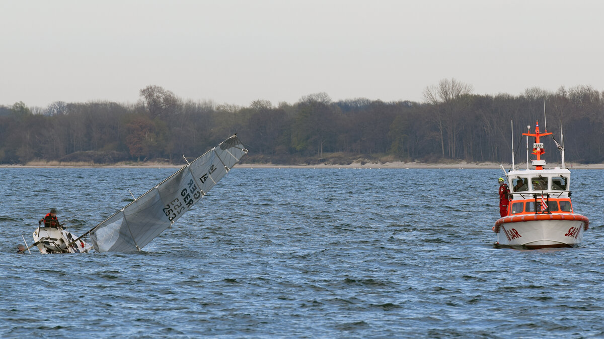 SAR-Boot ERICH KOSCHUBS nach Eintreffen bei gekentertem Segelboot. Ostsee vor Lübeck-Travemünde, 20.04.2022. Die Besatzung des Segelbootes ist dabei, ihr Fahrzeug aus eigener Kraft wieder aufzurichten