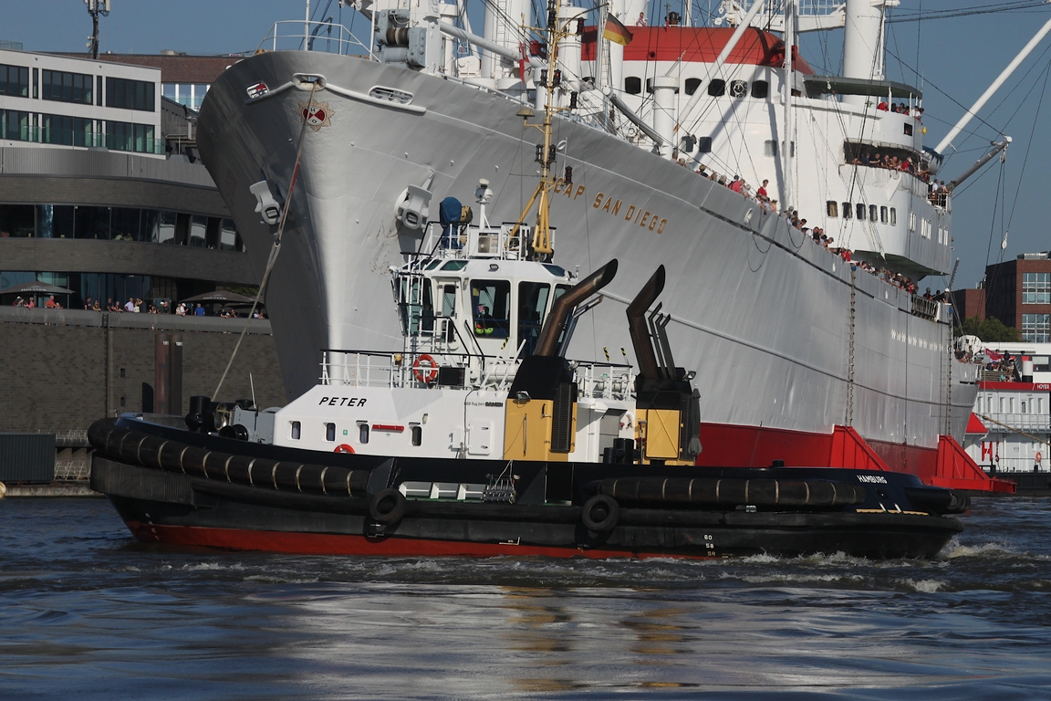 Schlepper PETER (IMO: 9445863); Datum: 19.08.2025; Aufnahmeort: Elbe/Hafen Hamburg, Deutschland. Das Bild zeigt die PETER beim „Einparken“ der von einer Traditionsfahrt zurück kommenden CAP SAN DIEGO am Anleger Überseebrücke.
