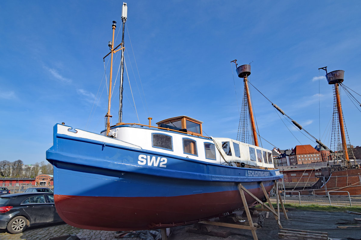 SW2 am 8.4.2020 bei den Media-Docks im Hafengebiet von Lübeck. Die Barkasse wurde auf der Werft J. Oelkers in Hamburg erbaut und unter dem Name „Fritz“ am 19. Mai 1925 erstmalig in Hamburg in Fahrt gesetzt. 1946 wurde die Barkasse umbenannt und unter dem Namen „Technischer Betrieb 1“ im Hamburger Hafen von der Reederei HAPAG eingesetzt. Ende 1972 erwarb die Schlichting-Werft in Lübeck-Travemünde das Fahrzeug, wo es dann als „SW 2“ bis zur Schließung der Werft Ende 1987 im Einsatz war. Mit dem Kauf des Werftgeländes durch die „Rosenhof“-Gruppe ging die Barkasse in deren Eigentum über, um nach Renovierungsarbeiten und der Umbenennung in „Elfriede“ als Ausflugsschiff der Senioren-Residenz „Rosenhof Travemünde“ eingesetzt zu werden. Am 26.11.1994 wurde die Barkasse als Sachspende an Gesellschaft Weltkulturgut Hansestadt Lübeck (gemeinnützig)e.V. übergeben.