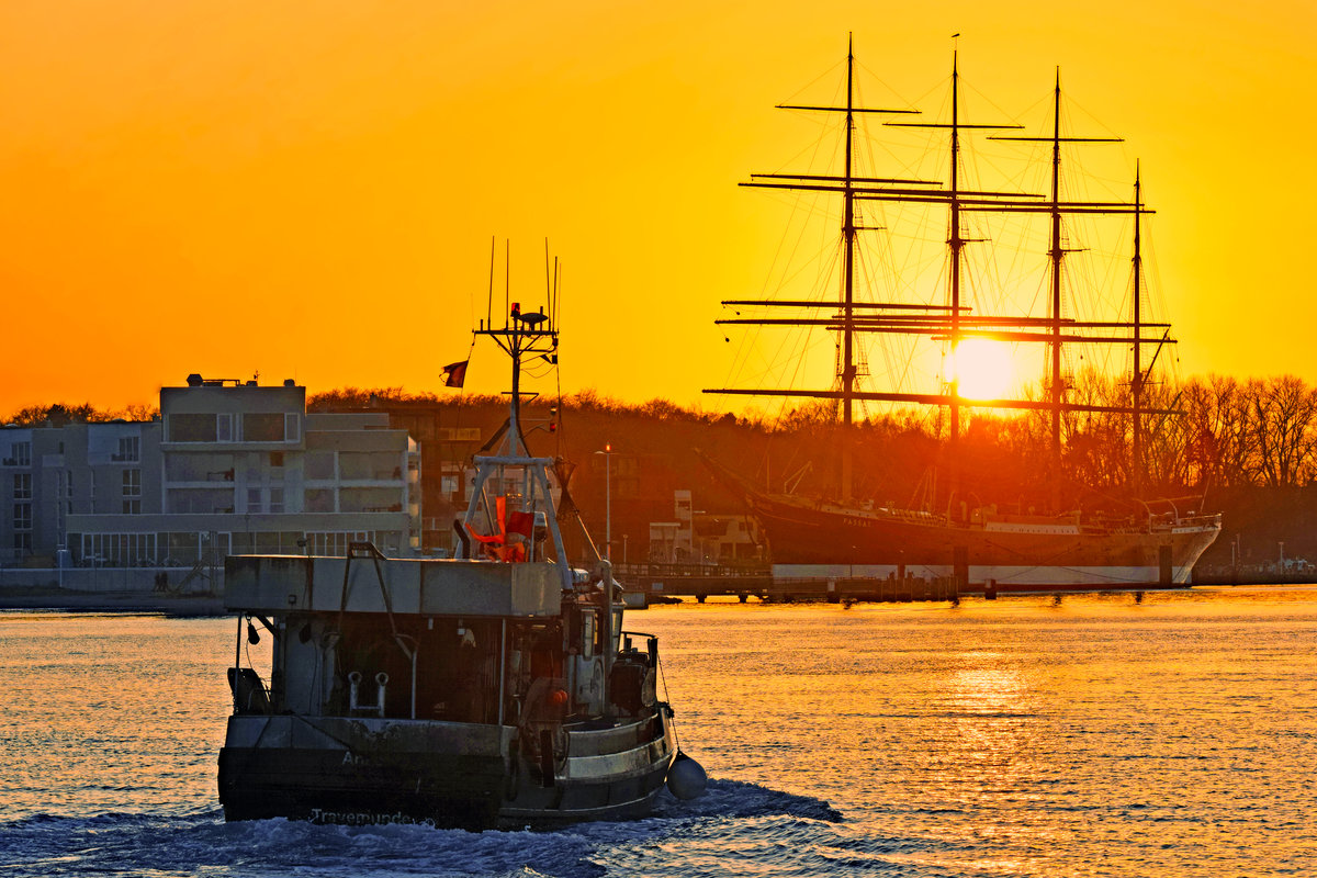 TRA 4 läuft bei untergehender Sonne am 19.01.2020 in den Hafen von Lübeck-Travemünde. Rechts im Bild ist die Viermastbark PASSAT zu sehen.