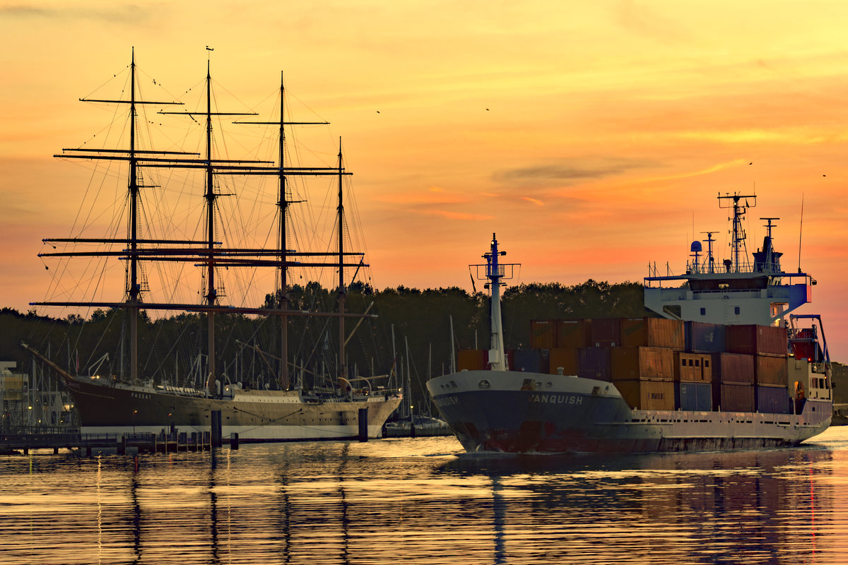 VANQUISH  (IMO: 9116199) fährt am Abend des 12.10.2018 im Licht der untergehenden Sonne an der in Lübeck-Travemünde liegenden Viermastbark PASSAT vorbei in Richtung Ostsee. 