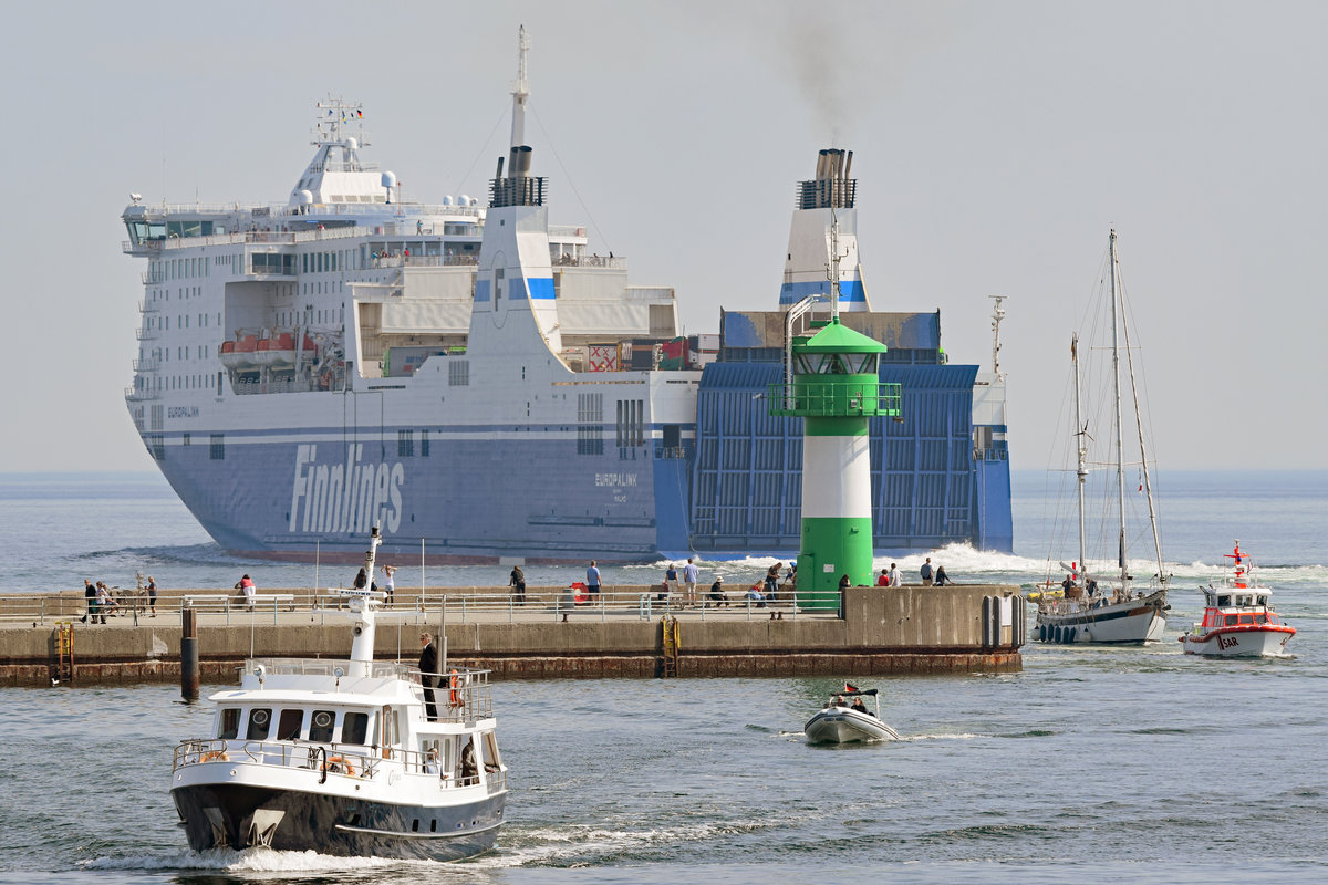 Während das Fährschiff EUROPALINK die Nordermole passiert und Lübeck-Travemünde hinter sich lässt, läuft die Motoryacht CETARA (u.a. für Seebestattungen eingesetzt)in den Hafen ein. HANS INGWERSEN von der Deutschen Gesellschaft zur Rettung Schiffbrüchiger hat ein Segelboot im Schlepp (ganz rechts im Bild). 