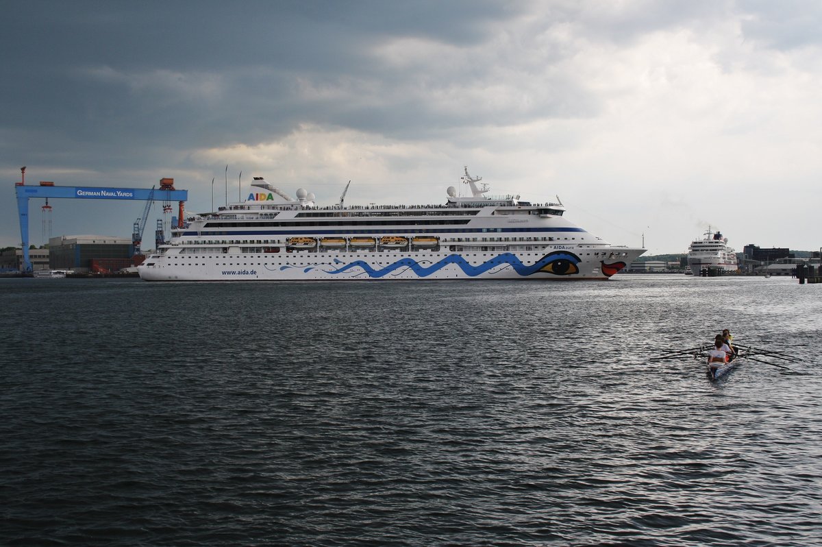 Während die MS Europa im Hintergrund noch festvertäut am Kieler Ostseekai liegt, verlässt AIDAaura am 22.5.2016 ihren Liegeplatz 