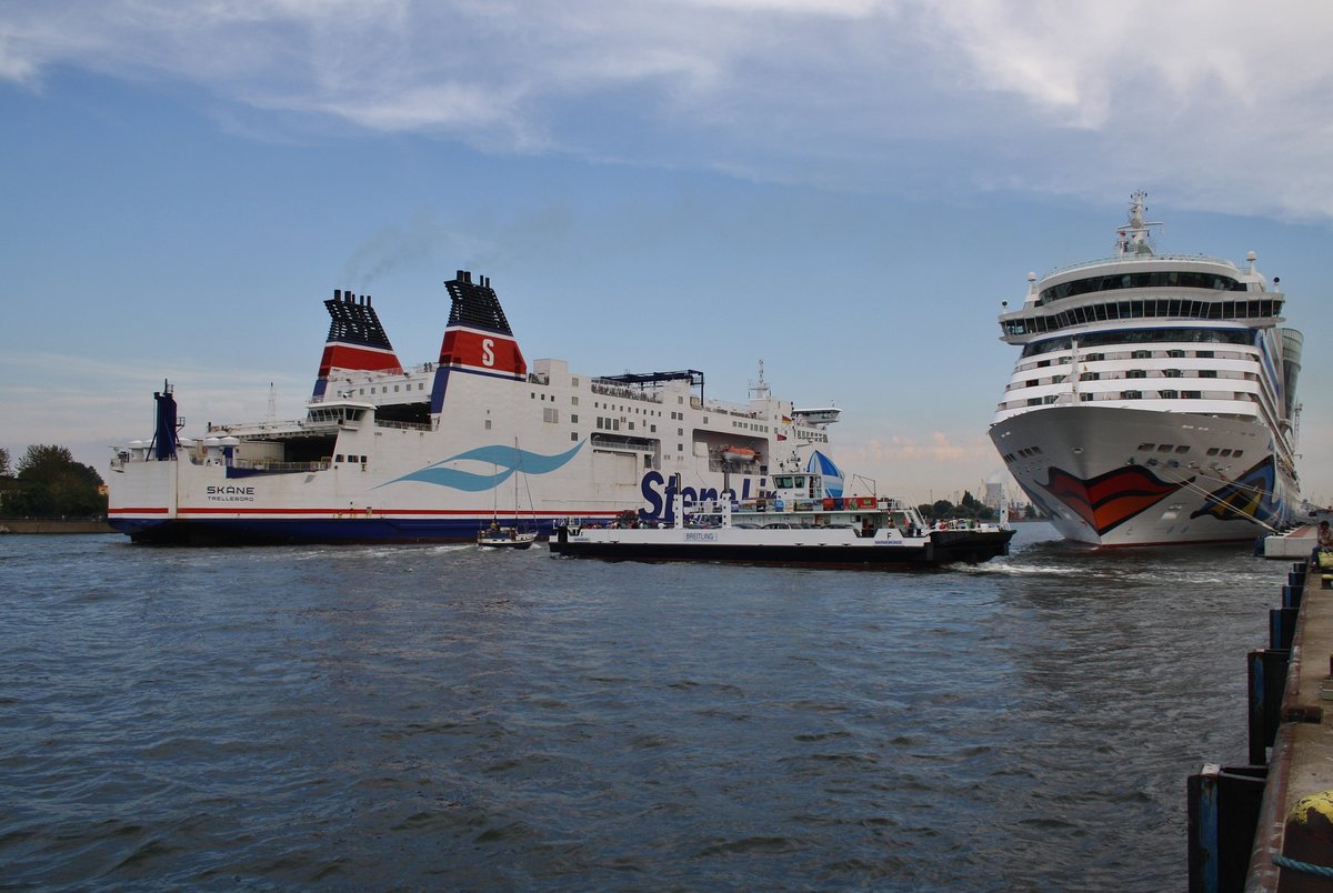 Während die Skåne aus Trelleborg kommend in Warnemünde einläuft, überquert das Fährschiff  Breitling  die Warnow. Am P7 hat AIDAdiva festgemacht und wird am Abend in Richtung Kopenhagen auslaufen. (28.8.2016)