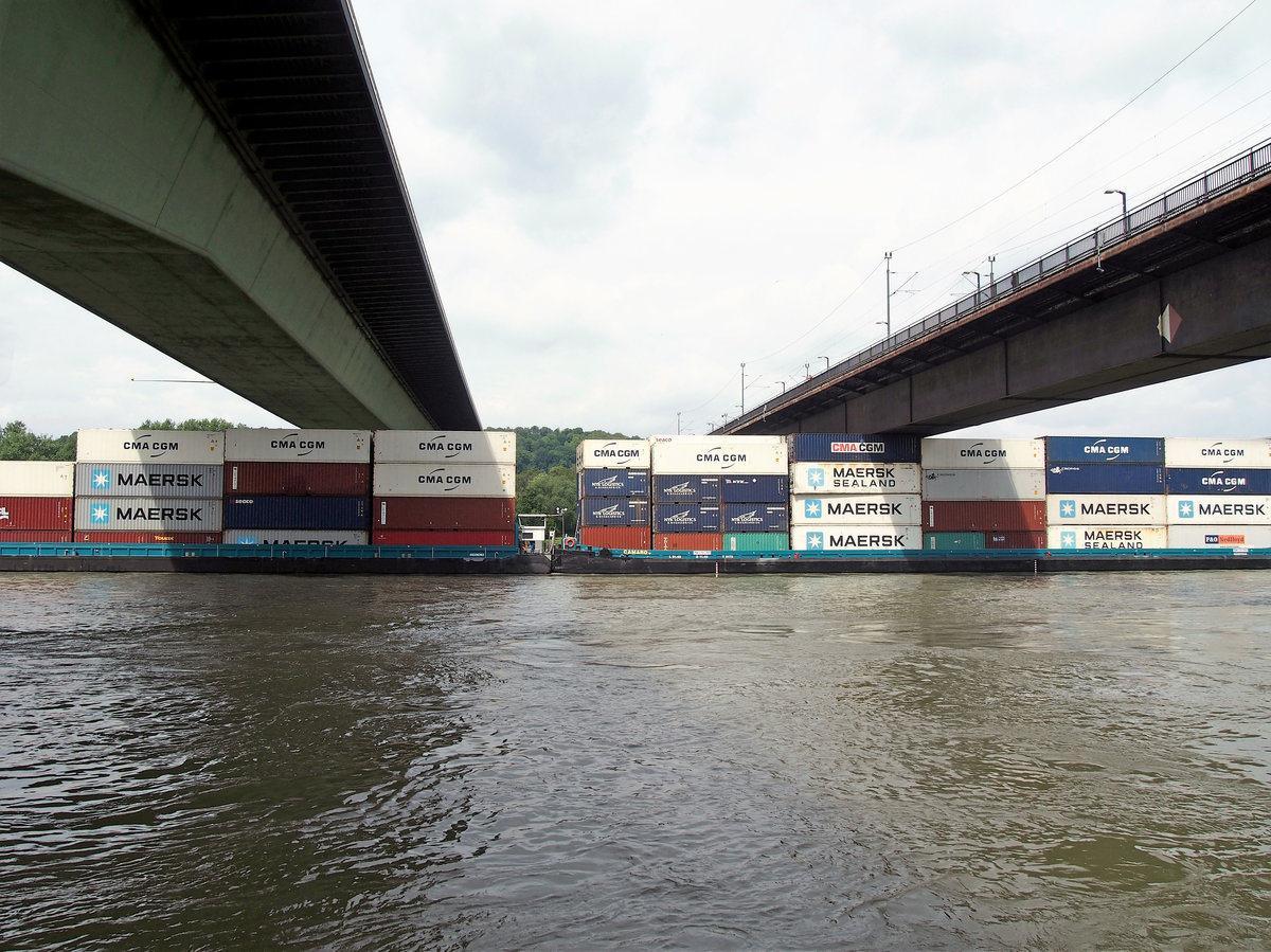 Wegen des viel zu geringen Abstandes kollidiert ein Container mit der Brücke; dadurch hat sich ein anderer Kühlcontainer deutlich verschoben. Als sich die Aufbauten unter der Brücke verkeilen, kommt der KVB zwischen Eisenbahnbrücke und der parallel verlaufenden, höheren Straßenbrücke zum Stehen. (20. Mai 2016)